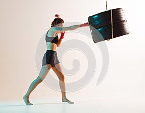 Cool female fighter trains jab on beige background in neon light. Women`s sport and motivation concept
