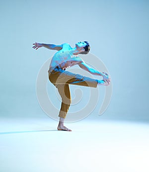 Cool flexible young man dancer dancing without shirt in neon blue light. Dance school poster. Dance lessons