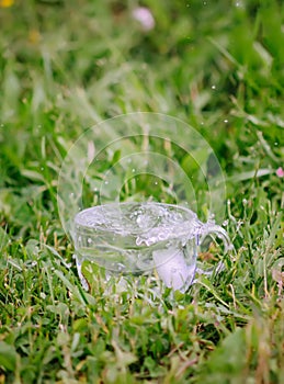 Cool fresh water with ice cubes in transparent glass cup outoors in summer day.