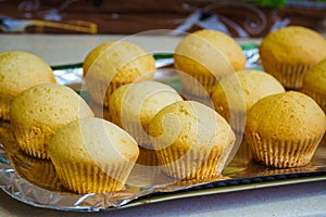 Cool freshly baked vanilla muffins on a metal sheet.