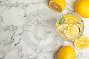 Cool freshly made lemonade and fruits on white marble table, flat lay. Space for text