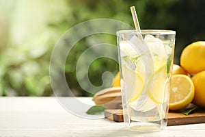 Cool freshly made lemonade and fruits on white wooden table, closeup. Space for text