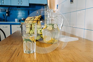 Cool freshly made lemonade in glass pitcher on wooden table. Summer drink Ice cold lemonade in glass and jug