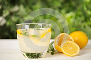 Cool freshly made lemonade in glass on white table