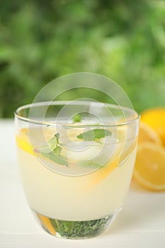 Cool freshly made lemonade in glass on white table