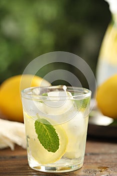 Cool freshly made lemonade in glass on wooden table