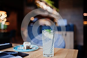 Cool freshly made lemonade in glass on wooden table at restaurant