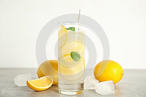 Cool freshly made lemonade, ice cubes and fruits on grey table