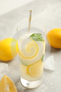 Cool freshly made lemonade, ice cubes and fruits on grey table