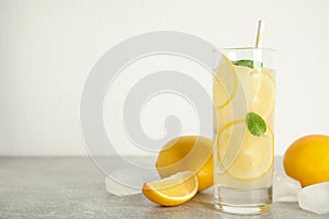 Cool freshly made lemonade, ice cubes and fruits on grey table. Space for text