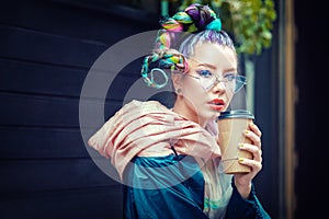 Cool funky young girl with piercing and crazy hair enjoy takeaway coffee on street