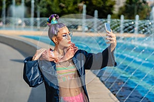 Cool funky young woman with fashion outfit taking selfie outdoor