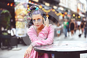 Cool funky young woman with trendy eyeglasses and avant-garde style listening music on headphones outdoor, hipster girl enjoy mus