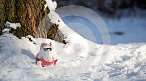 Cool funny Santa Claus with sun glasses sitting on the snow