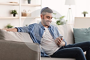 Closeup of smiling jewish man using smartphone at home