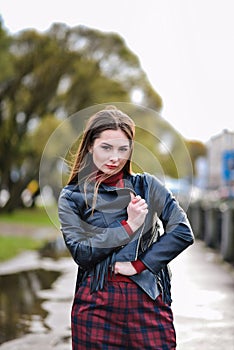 Cool girl in a black leather biker jacket walks around the city