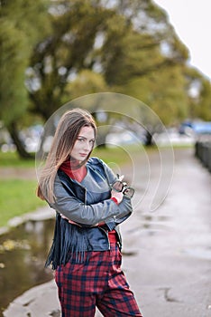 Cool girl in a black leather biker jacket walks around the city