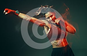 Cool girl fighter with relief abs makes jab in studio in neon light. Sport and motivation concept. Long exposure shot photo