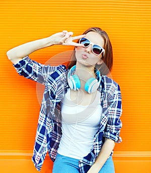 Cool girl having fun listens music in headphones over colorful