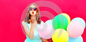 Cool girl is sends an air kiss holds an air colorful balloons
