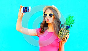 Cool girl taking picture self portrait on smartphone with pineapple