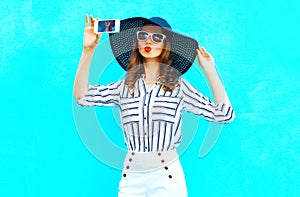 Cool girl is taking a picture on a smartphone wearing a straw hat