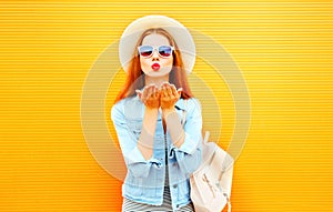 Cool girl young woman sends an air kiss on orange background