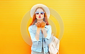 Cool girl young woman sends an air kiss on orange background photo