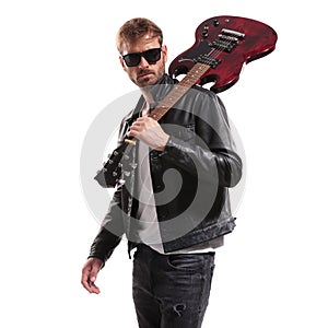 Cool guitarist in black leather jacket posing with his guitar