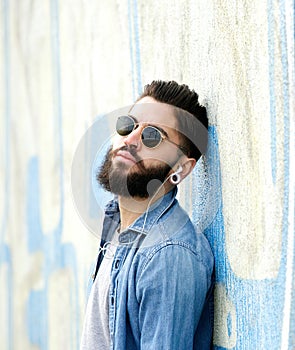 Cool guy with beard listening to music with earphones
