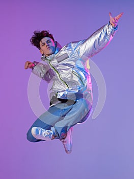 Cool guy dancing contemporary dance in studio. Neon light background. Acrobatic bboy dancer. Break dance lessons.