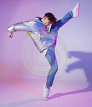 Cool guy dancing contemporary dance in studio. Neon light background. Acrobatic bboy dancer. Break dance lessons.