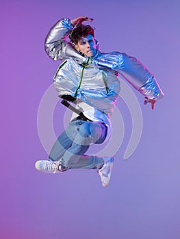 Cool guy dancing contemporary dance in studio. Neon light background. Acrobatic bboy dancer. Break dance lessons.