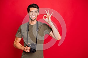 Cool guy with photo digicam showing okey symbol had tested new camera wear t-shirt isolated on red background