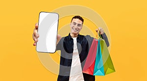 Cool guy showing smartphone and purchases, shopping online