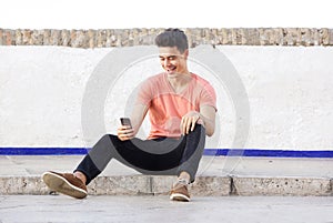 Cool guy sitting on sidewalk looking at mobile phone