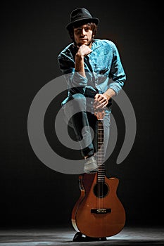 Cool guy standing with guitar on dark background