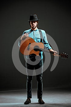 Cool guy standing with guitar on dark background