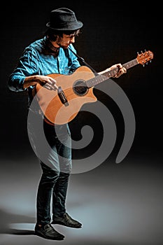 Cool guy standing with guitar on dark background