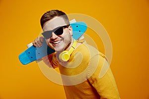 Cool guy wearing yellow jumper and sunglasses holding longboard on shoulders looking super excited