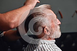 Cool hairstyle for real men, stylist combing his client`s hair with fantastic neatness