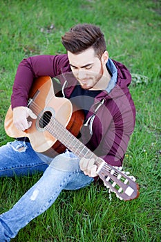 Cool handsome guy playing guitar at outside
