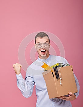 Cool happy man with a cardboard box with pens, plant and different things