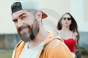 Cool hipster. Brutal man with long beard and mustache. Hipster street fashion. Attractive guy in front of girl