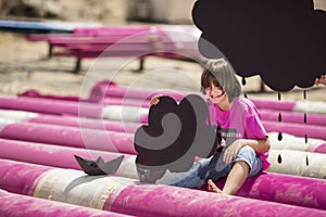 Cool kid plays on a pink pipes with black paper boats and clouds on construction site