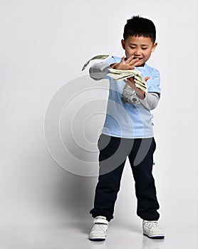 Cool little asian boy throwing money cash studio shot