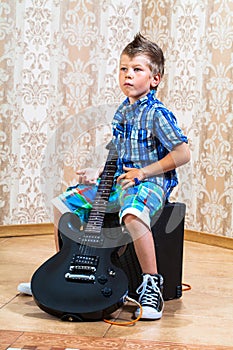 Cool little boy posing with electric guitar.