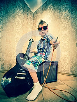 Cool little boy posing with electric guitar.