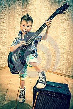 Cool little boy posing with electric guitar.