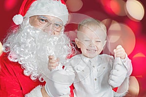 Cool little boy and Santa Claus at Christmas holiday